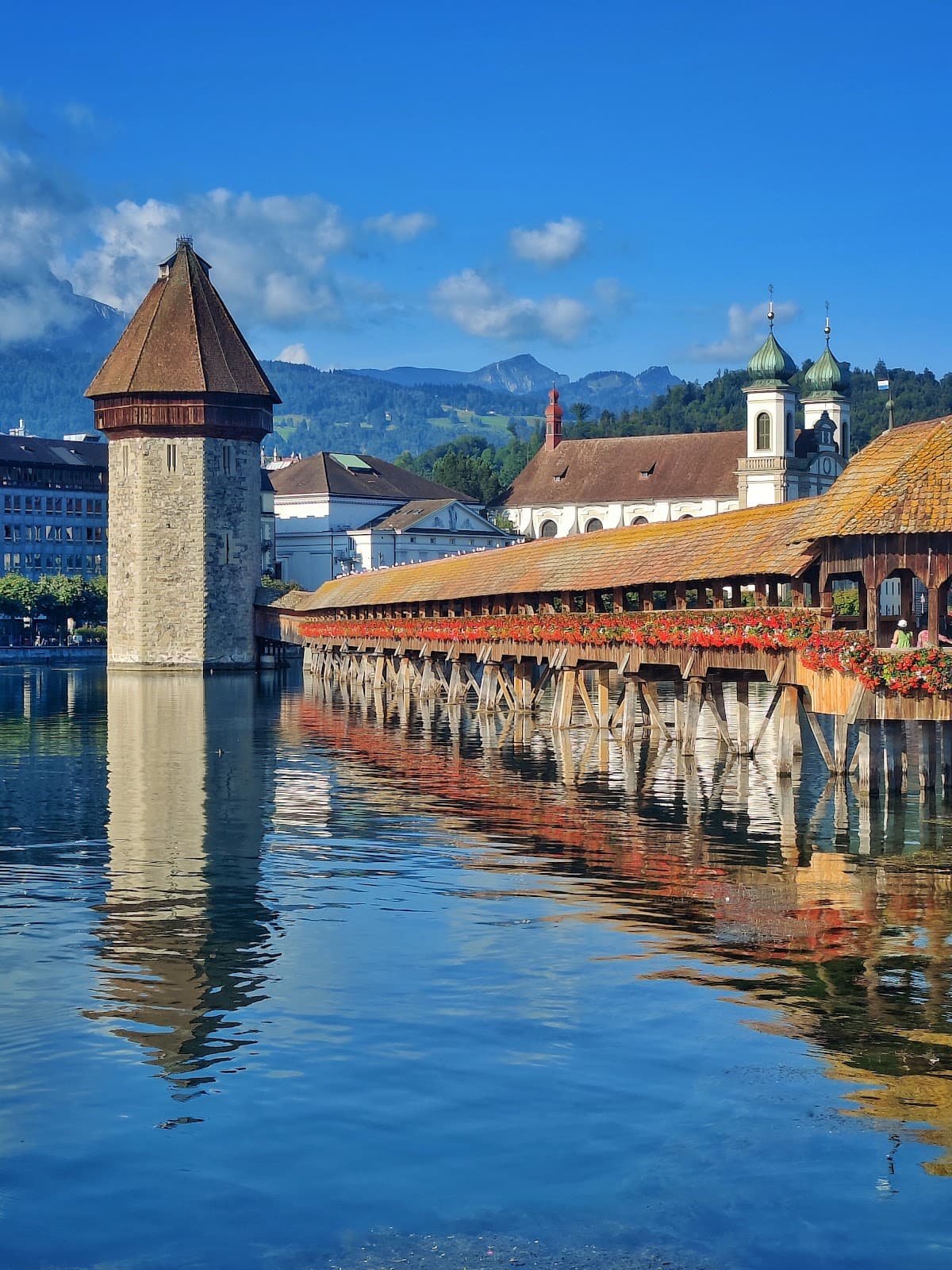 Iconic Chapel Bridge and Water Tower in Lucerne under a clear blue sky.